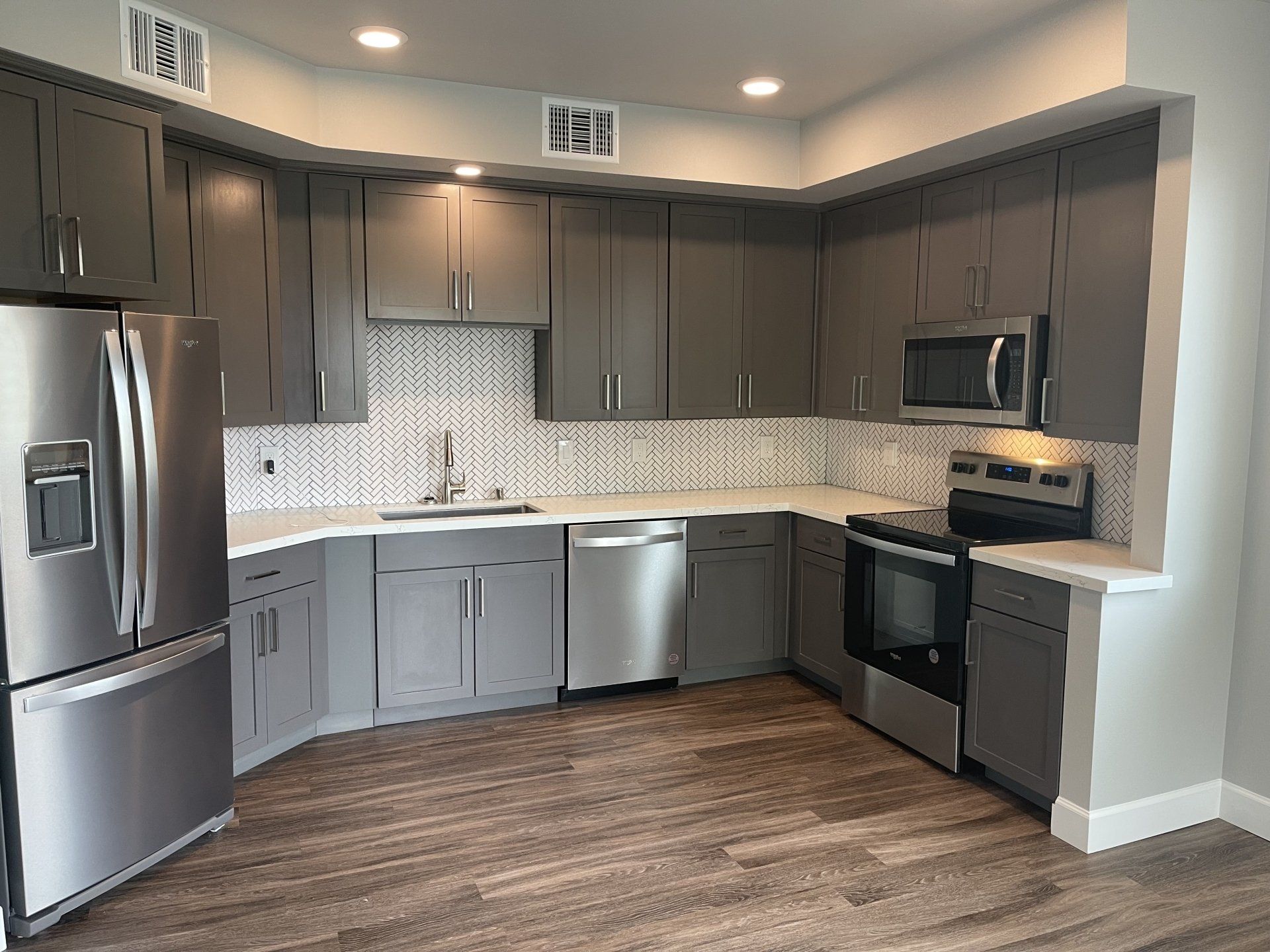 A kitchen with gray cabinets and stainless steel appliances at Capitol Towers.