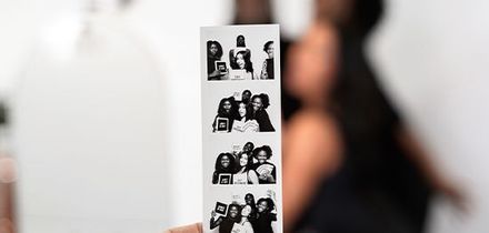 A black and white photo booth photo with a woman in the background.