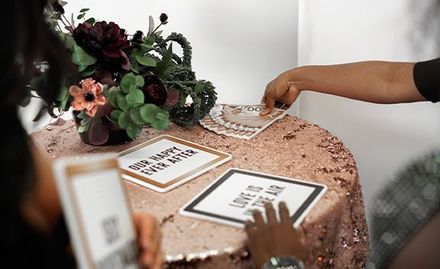 A person is grabbing a photo booth prop on a table with flowers on it.