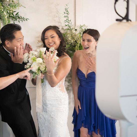 A bride and her bridesmaid are posing for a picture in front of a photo booth.