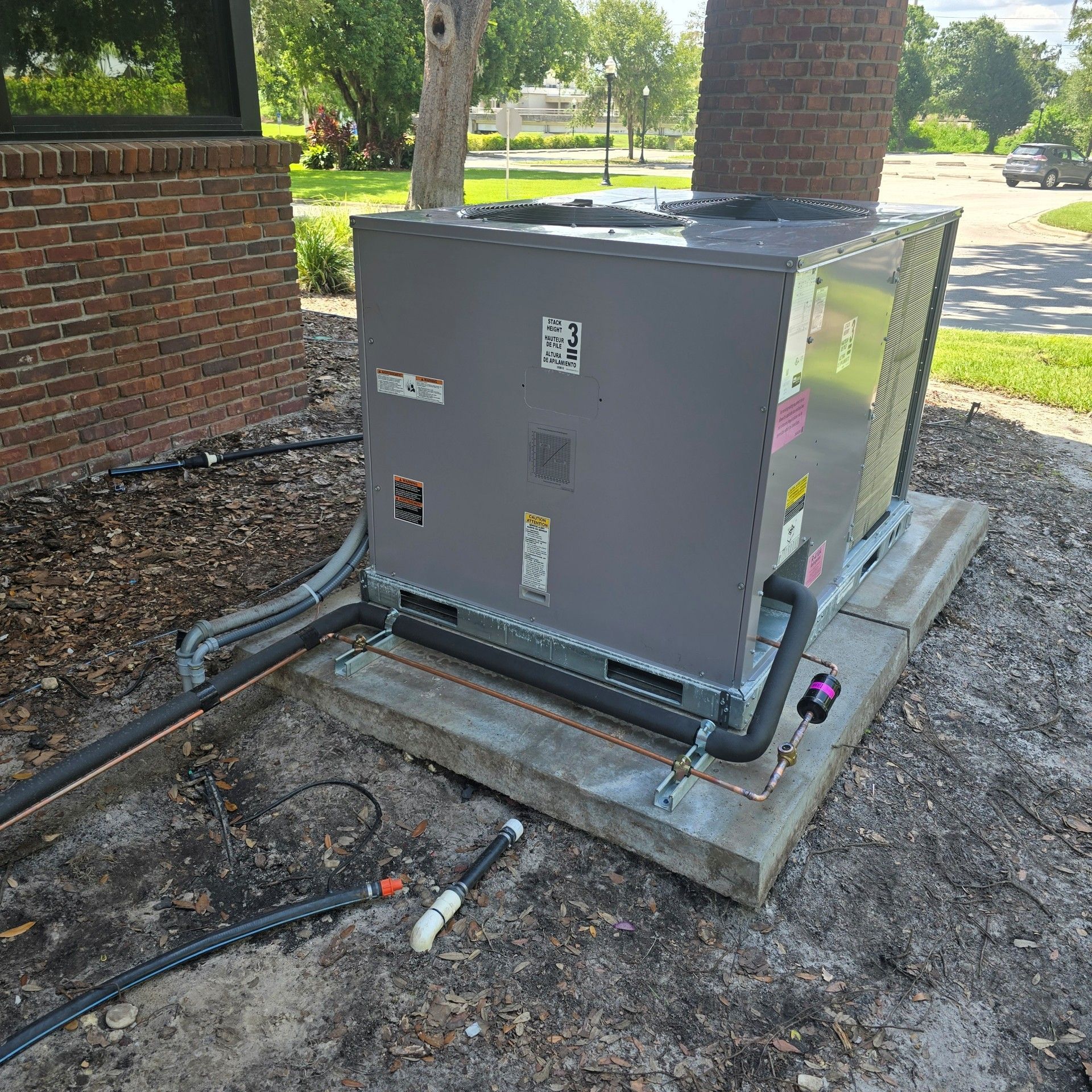 A technician uses a multimeter to inspect the wiring of an industrial air conditioning unit installed in a ceiling.