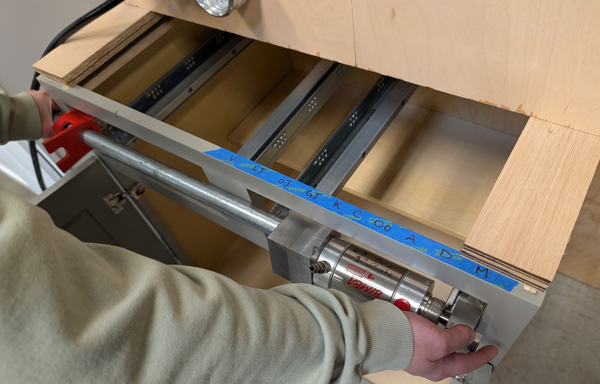 A Capital Testing Technician prepares to mount the base front loading fixture to a cabinet