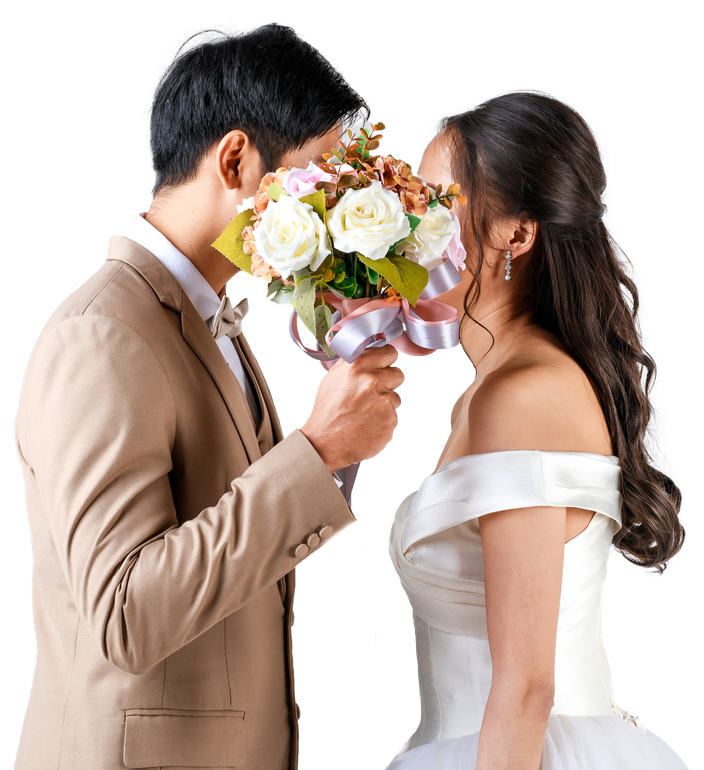 Young attractive Asian couple, man wearing beige suit, woman wearing white wedding gown standing looking at each other holding bouquet of flower. Concept for pre wedding photography.
