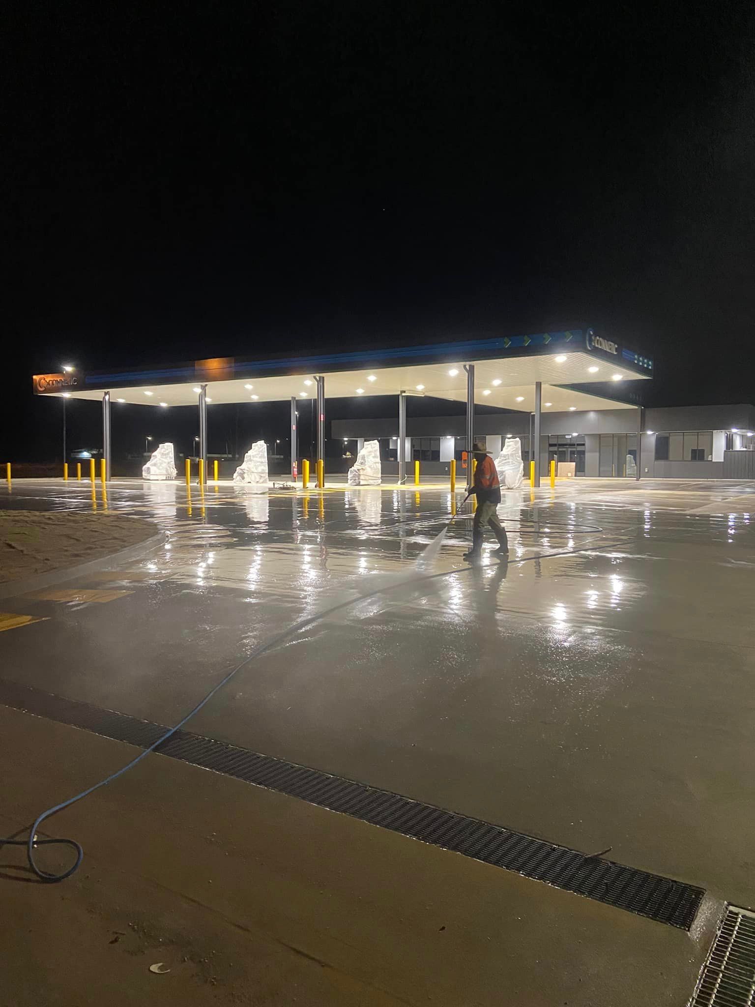Worker Cleaning The Driveway In Gasoline Station Using High Pressure Washer — High Pressure Cleaning Service In Tamworth, NSW