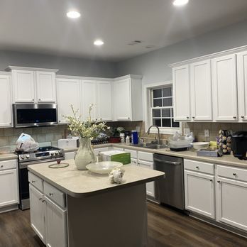 White kitchen with island, stainless steel appliances, and light-colored countertops.