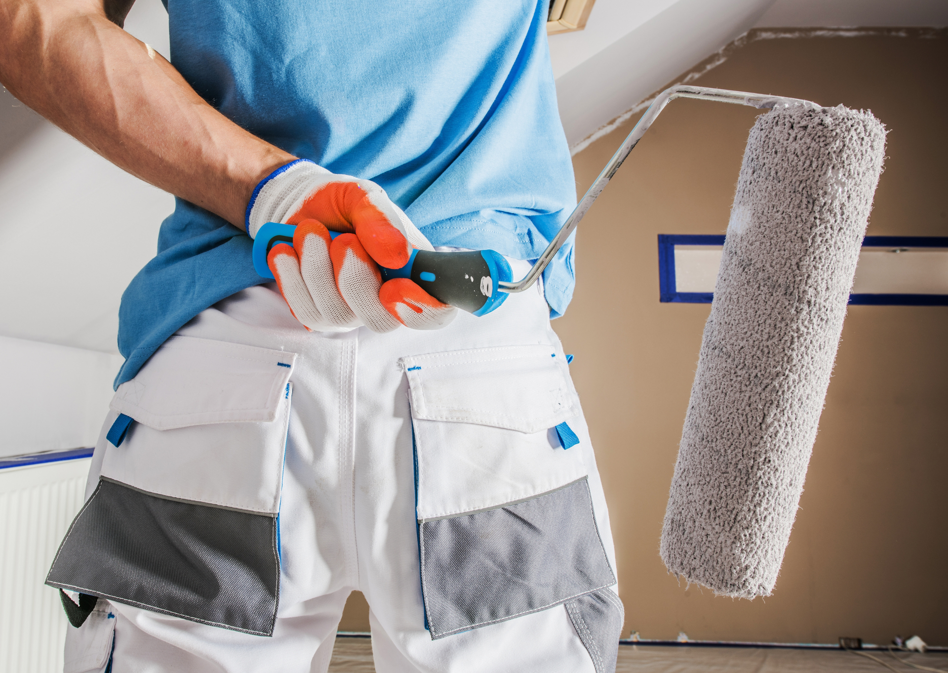 Painter in work clothes holding paint roller.