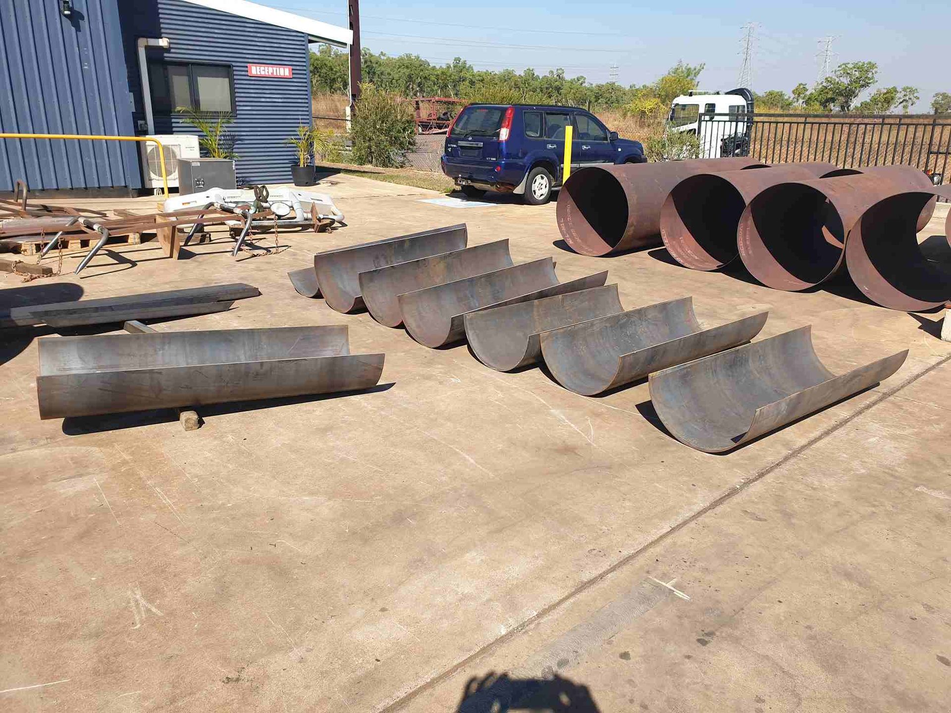 A Bunch of Metal Pipes Are Lined Up on the Ground — Roll Press NT In Tivendale, NT