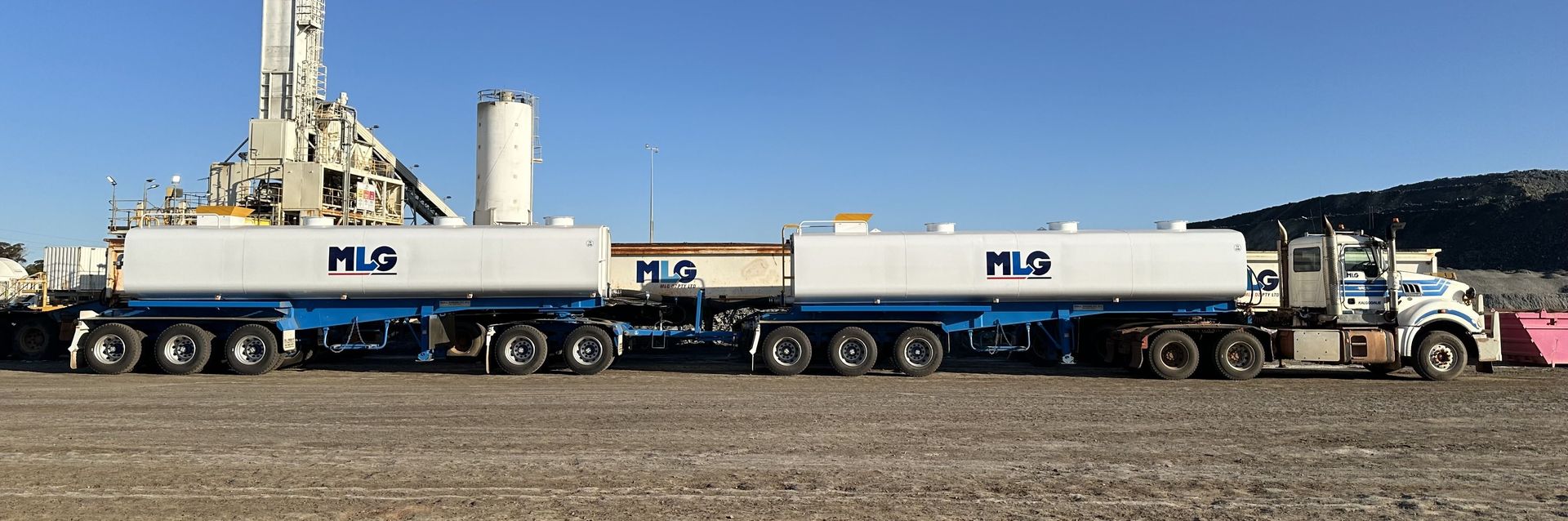 A Large White Truck With a Blue Trailer is Parked in a Dirt Field — Roll Press NT In Kununurra, WA