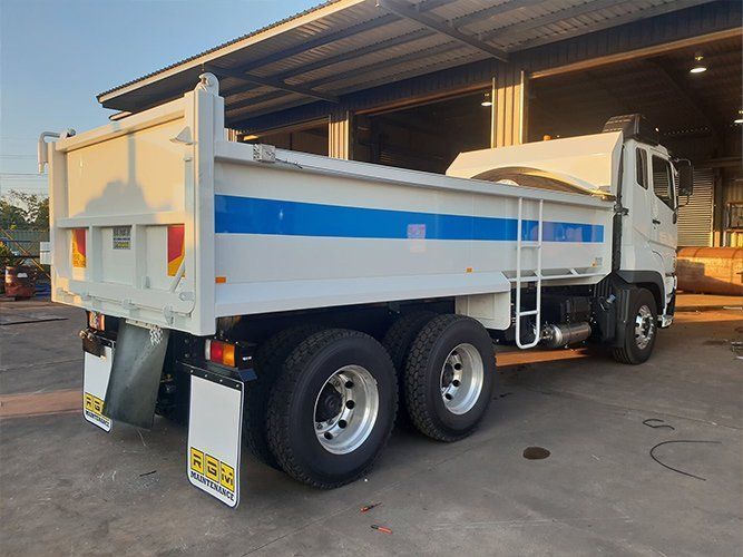 A White Dump Truck is Parked in Front of a Building — Roll Press NT In Tivendale, NT