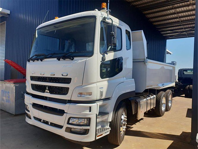 A White Dump Truck is Parked in Front of a Building — Roll Press NT In Tivendale, NT