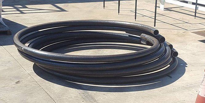 A Bunch of Black Pipes Are Rolled Up on the Ground — Roll Press NT In Tivendale, NT