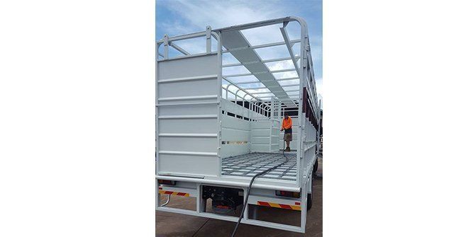 A Man is Standing in the Back of a White Truck — Roll Press NT In Tivendale, NT