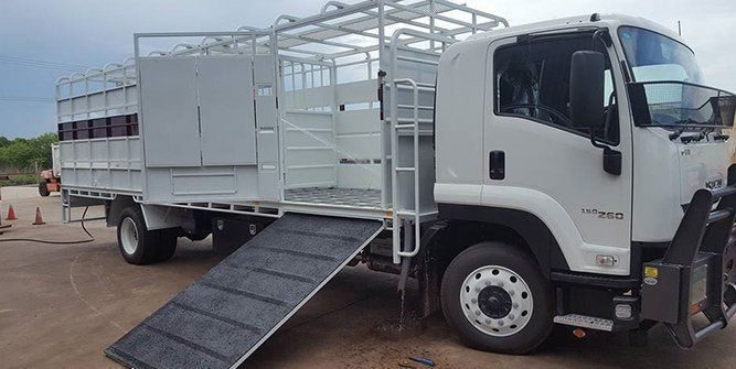 A White Truck With a Ramp on the Side is Parked in a Dirt Lot — Roll Press NT In Tivendale, NT