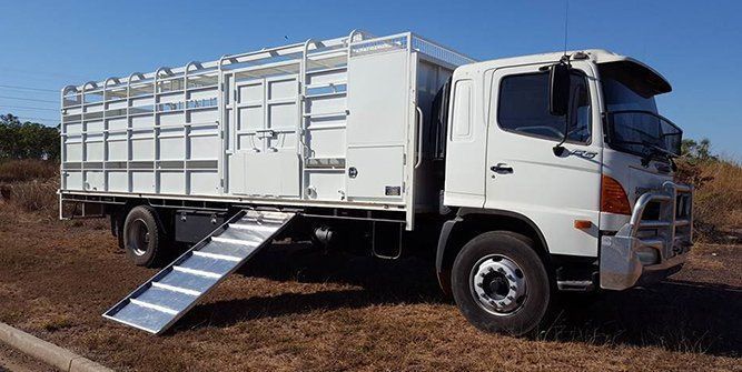 A White Truck With a Ramp on the Side is Parked in a Field — Roll Press NT In Tivendale, NT
