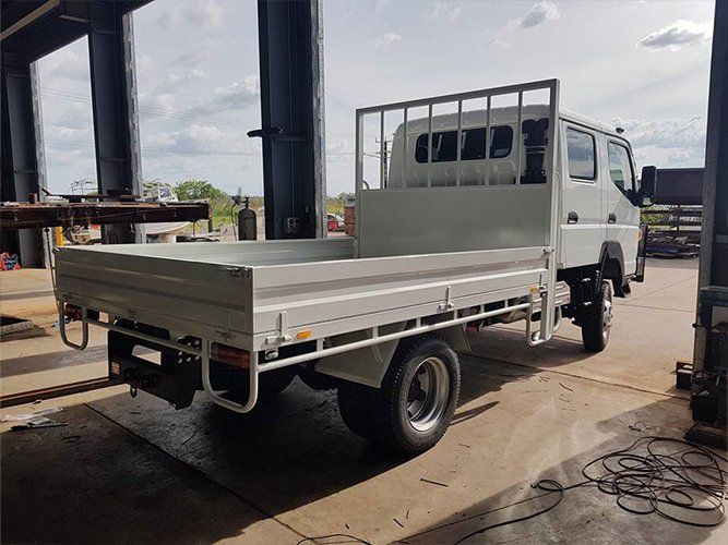 A White Truck With a Flat Bed is Parked in a Garage — Roll Press NT In Tivendale, NT