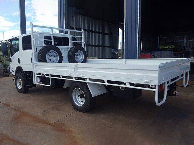 A White Truck With a Flat Bed is Parked in Front of a Building — Roll Press NT In Tivendale, NT