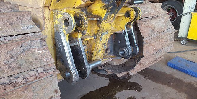 A Close Up of a Yellow Bulldozer's Tracks in a Garage — Roll Press NT In Tivendale, NT