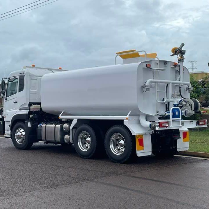 A White Tanker Truck is Parked on the Side of the Road in Front of a Building — Roll Press NT In Tivendale, NT