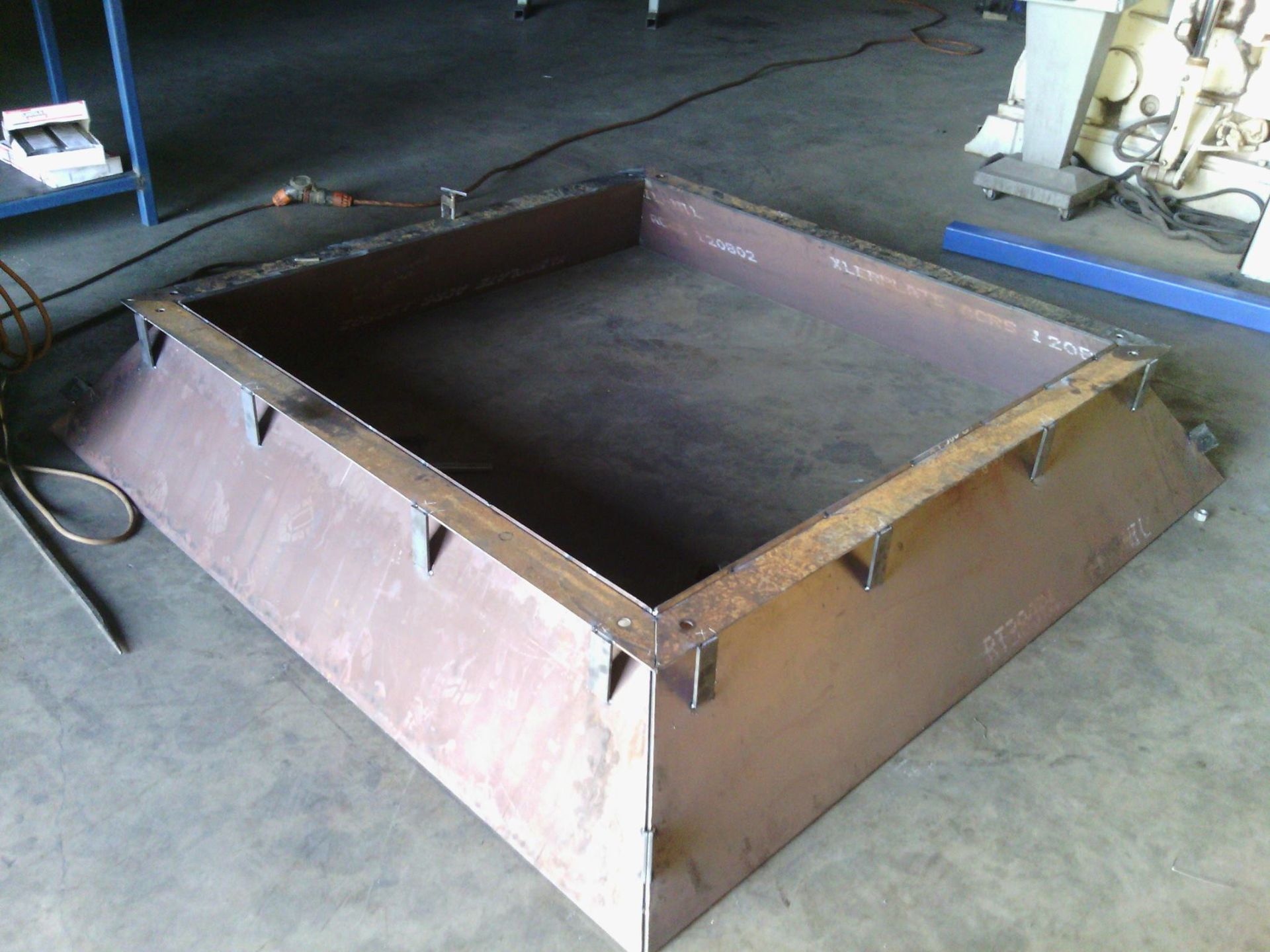 A Large Metal Box is Sitting on a Concrete Floor — Roll Press NT In Palmerston, NT