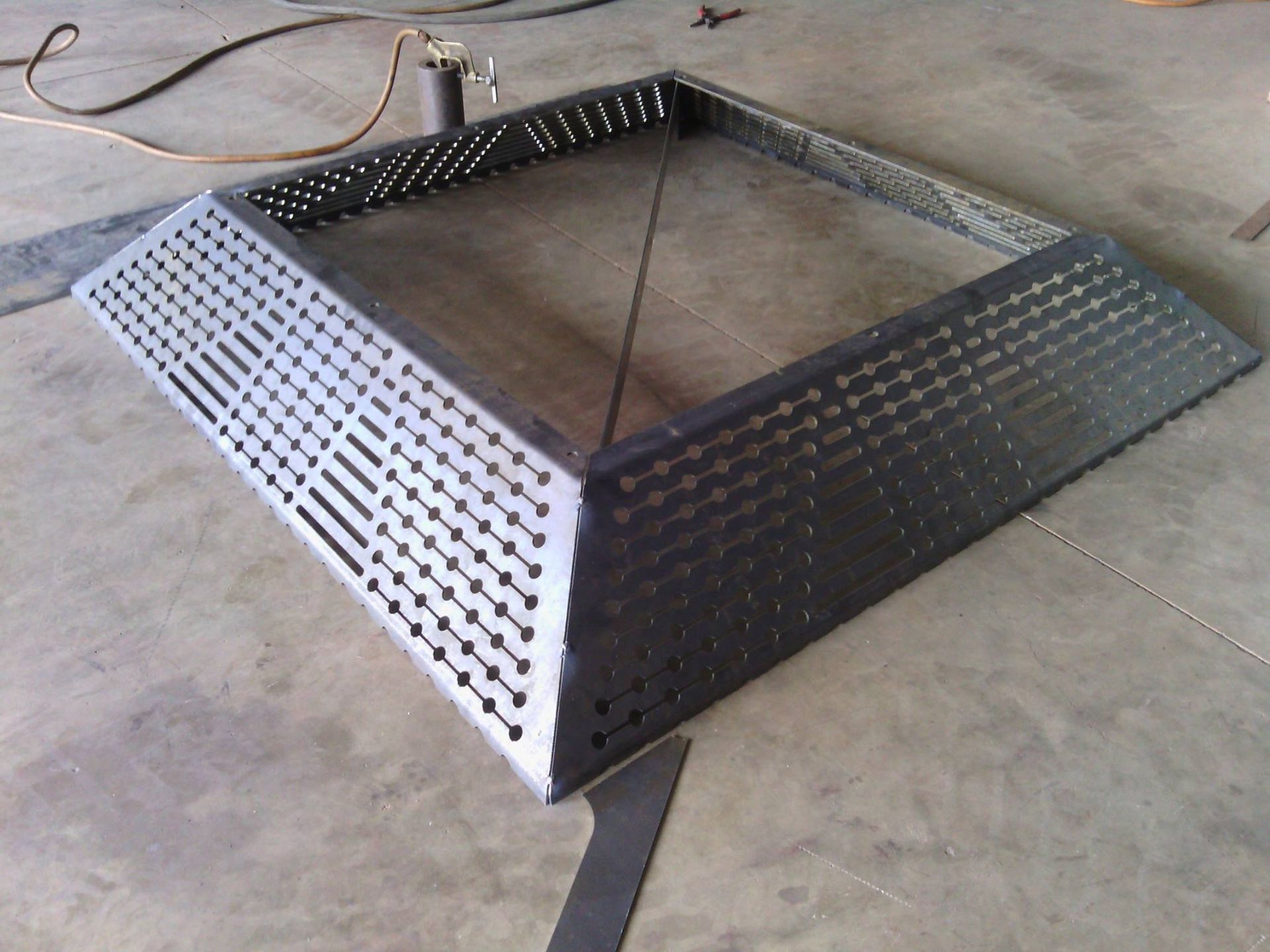 A Metal Item With Holes in It is Sitting on a Concrete Floor — Roll Press NT In Palmerston, NT