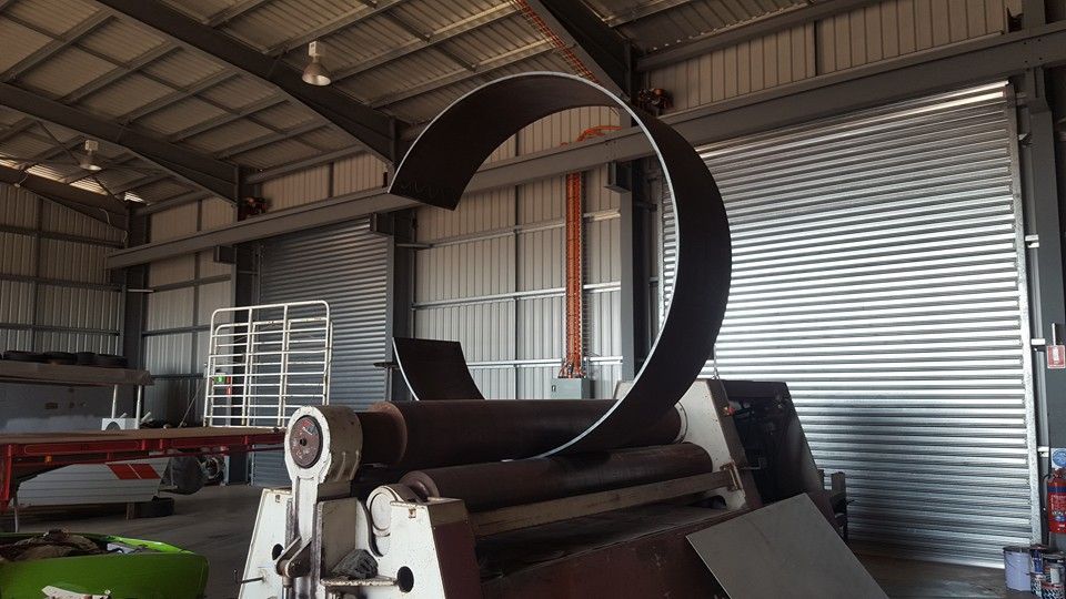 A Large Metal Pipe is Being Rolled on a Machine in a Warehouse — Roll Press NT In Alice Springs, NT