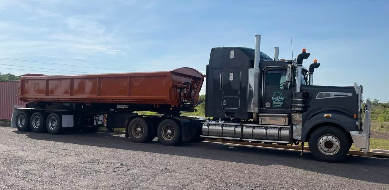 A Semi Truck With a Dump Trailer Attached to It is Parked on a Gravel Road — Roll Press NT In Tivendale, NT