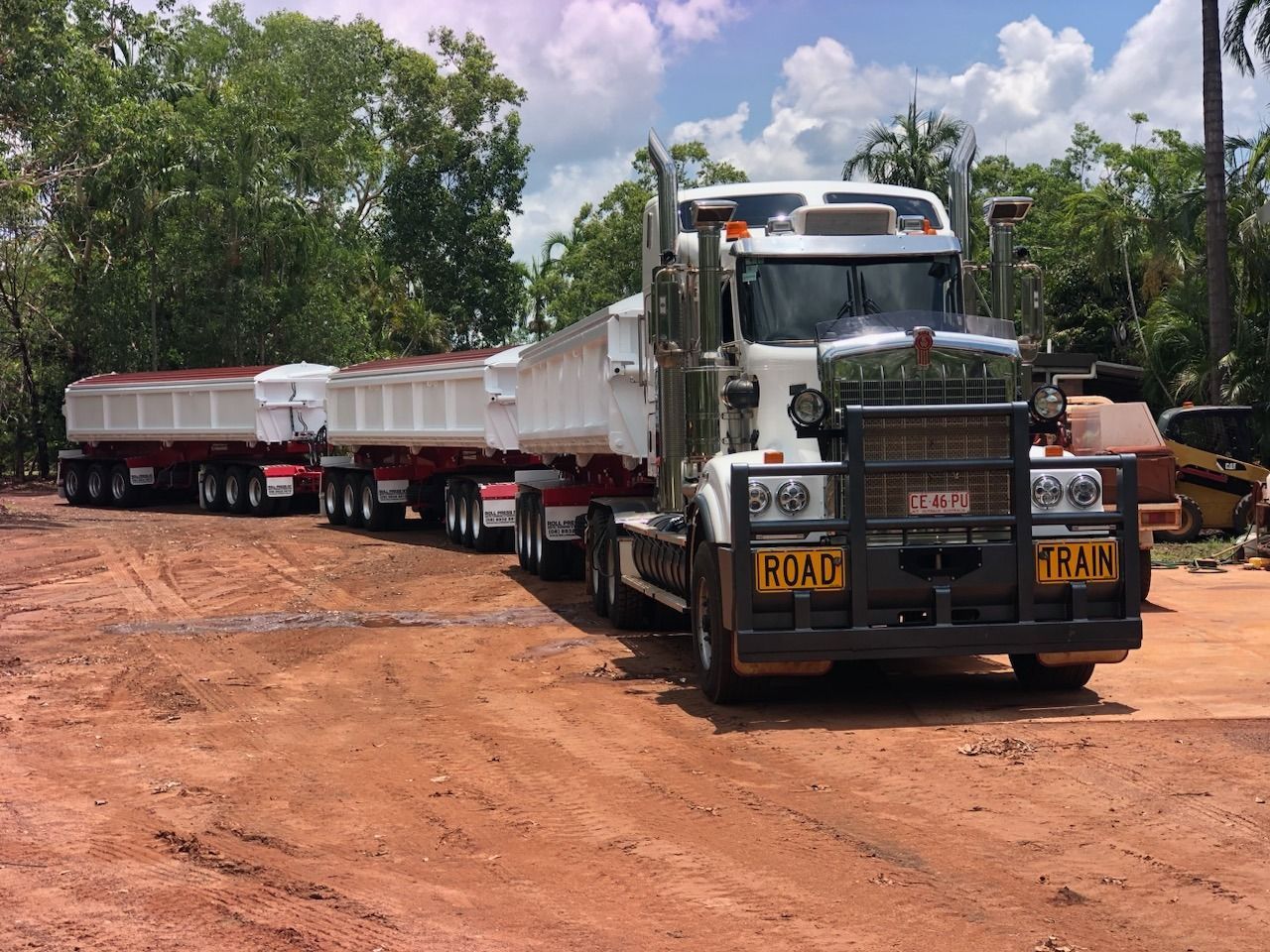 A Dump Truck With a Trailer Attached to It is Parked in a Dirt Lot — Roll Press NT In Tivendale, NT