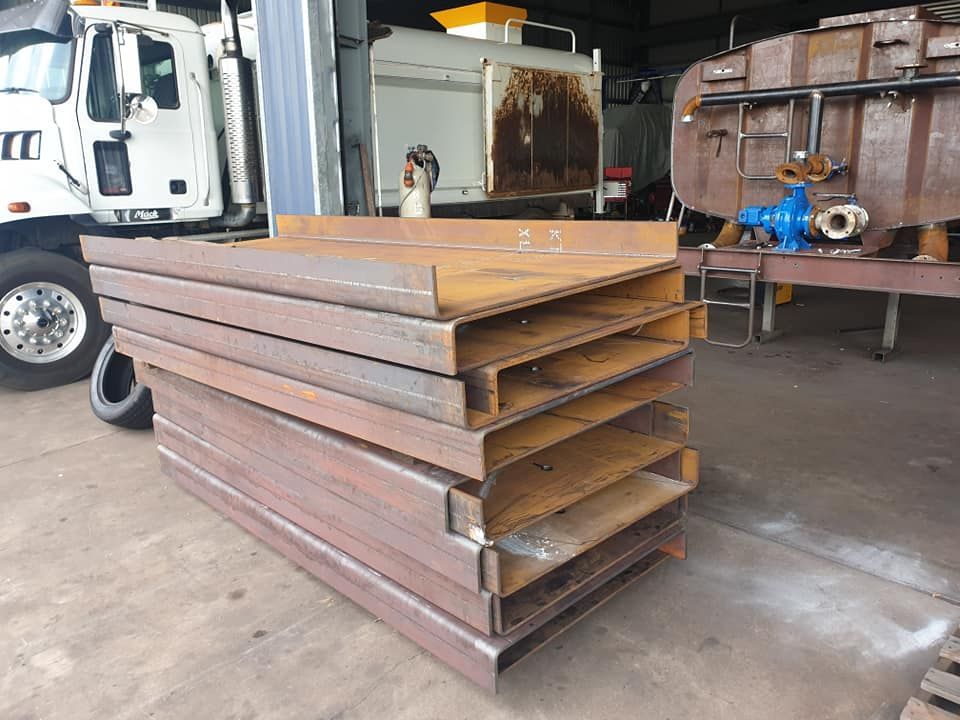A Stack of Metal Pipes is Sitting in a Garage Next to a Truck — Roll Press NT In Tivendale, NT