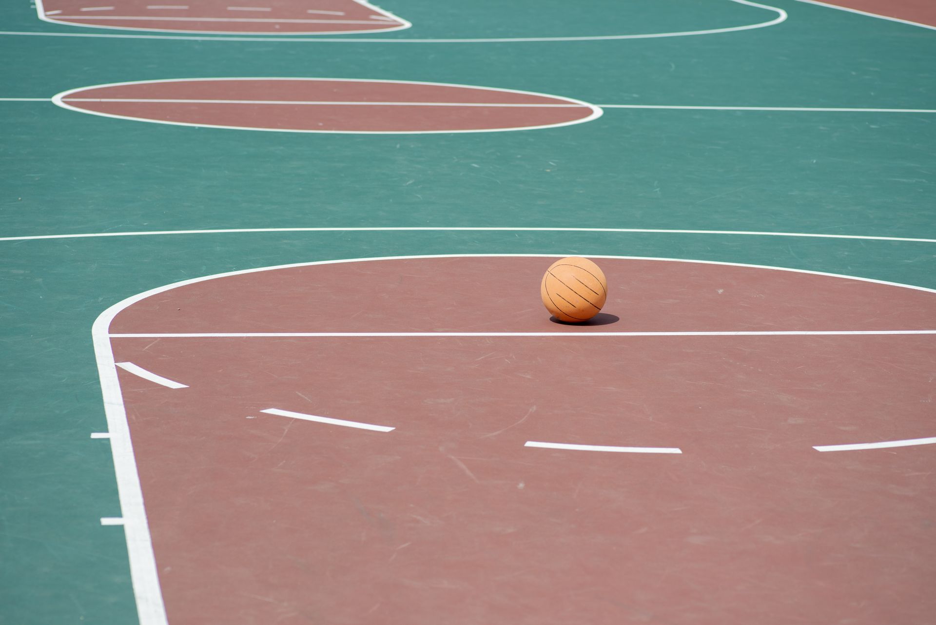 Basketball on a maroon court with green surrounds.