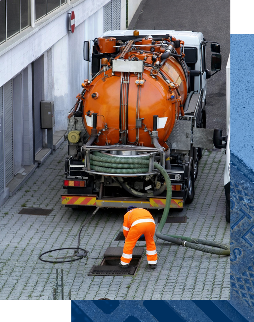 Worker in orange suit servicing a sewer with an orange tank truck.