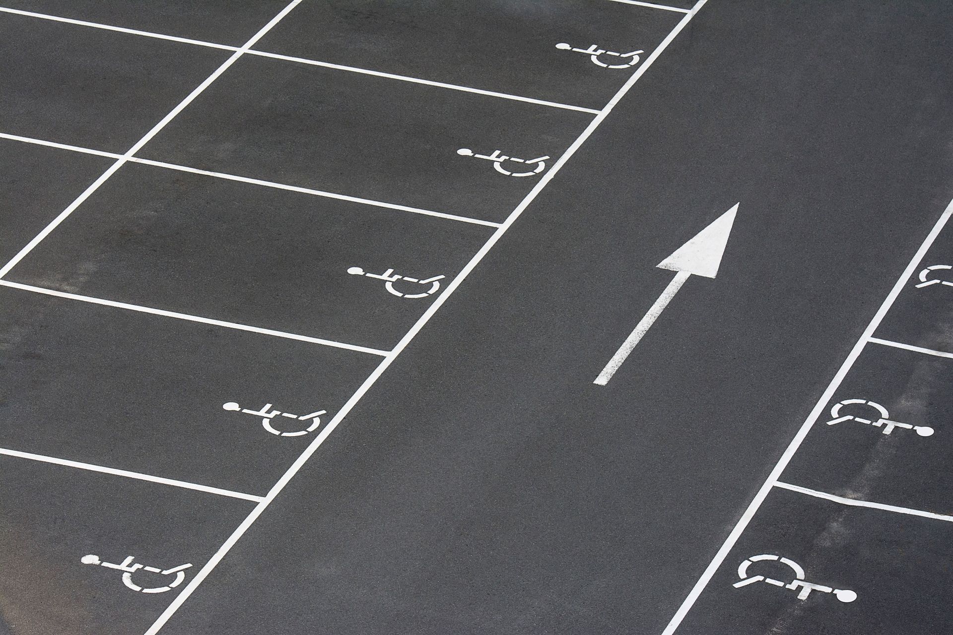 Empty parking lot with white lane markings and a directional arrow on dark asphalt