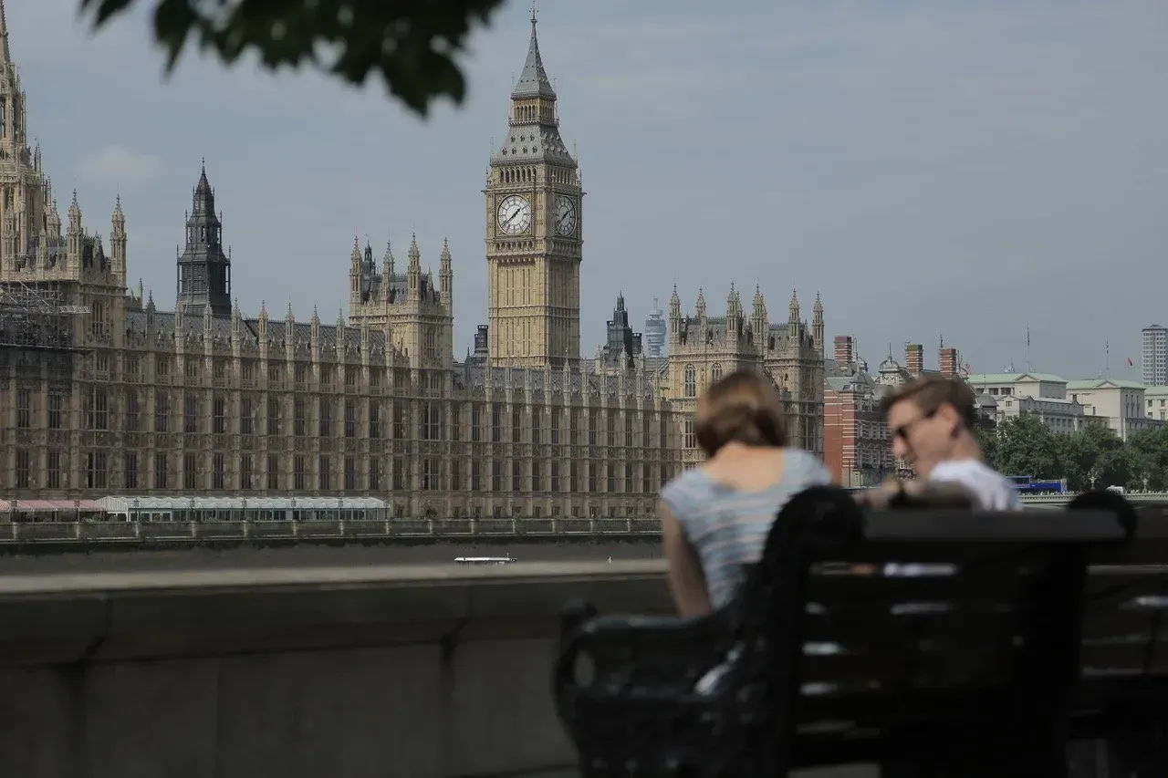 Um homem e uma mulher sentam-se em um banco em frente ao big ben