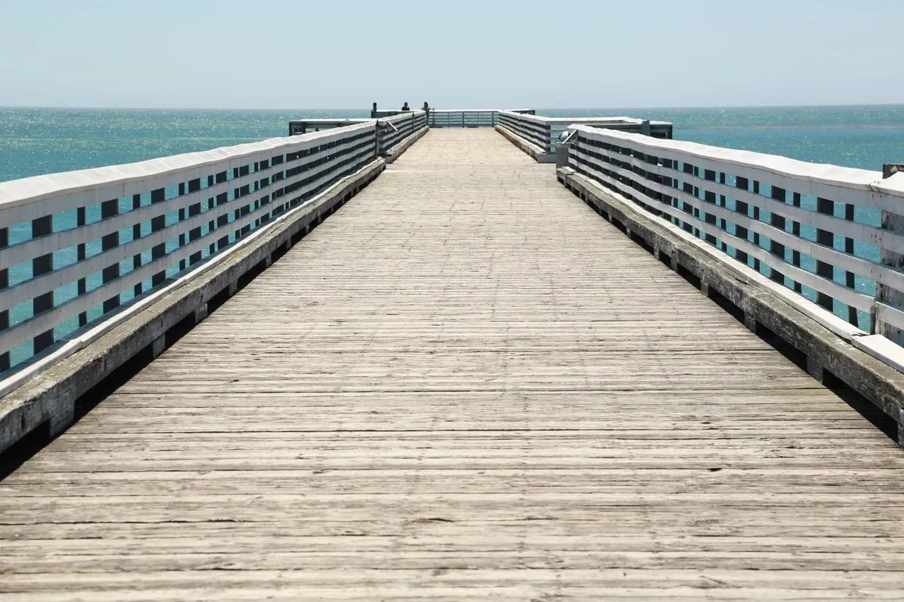 Um longo píer de madeira que leva ao oceano.