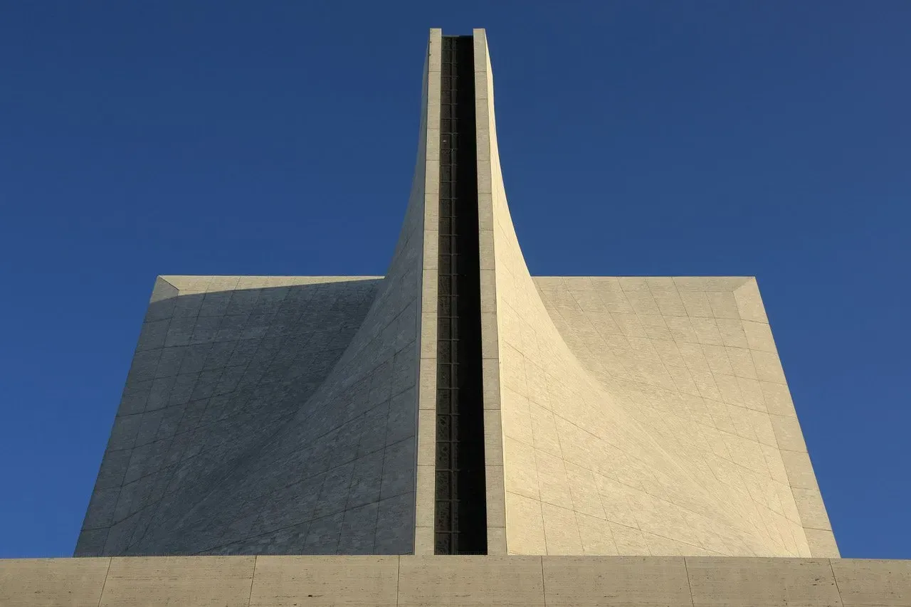 Um prédio muito alto com um céu azul ao fundo