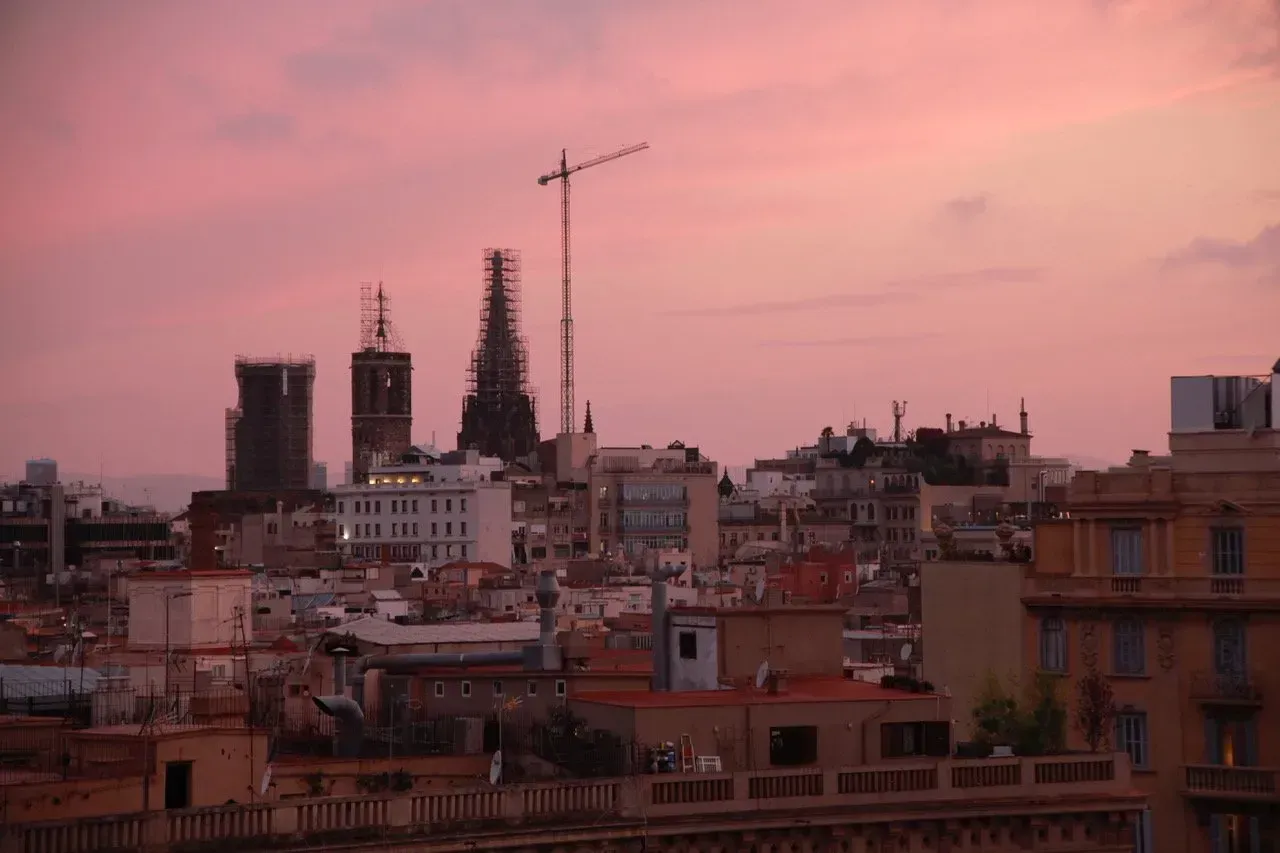 Um horizonte de cidade ao pôr do sol com um céu rosa ao fundo.