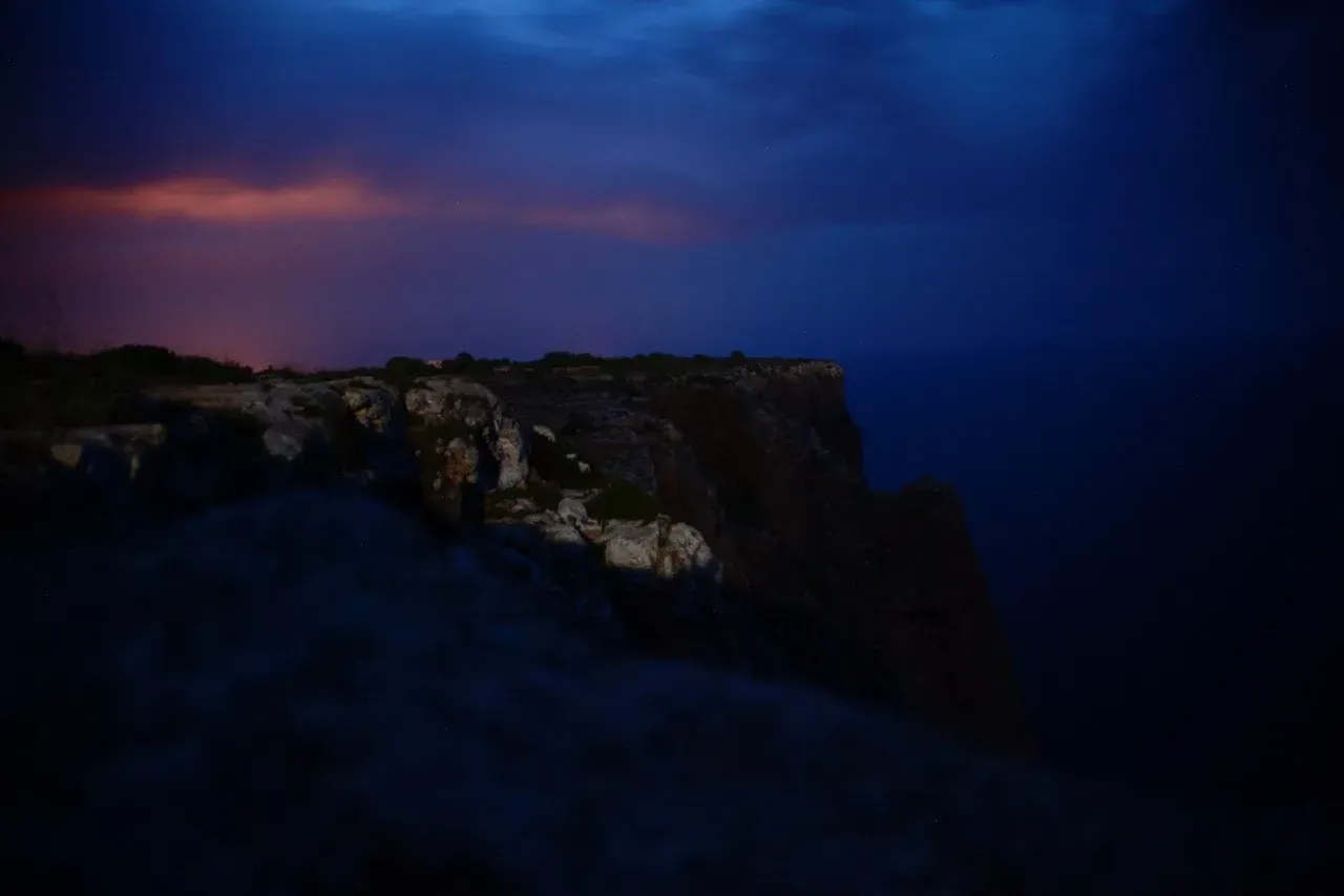 Uma imagem borrada de um penhasco com vista para o oceano à noite.