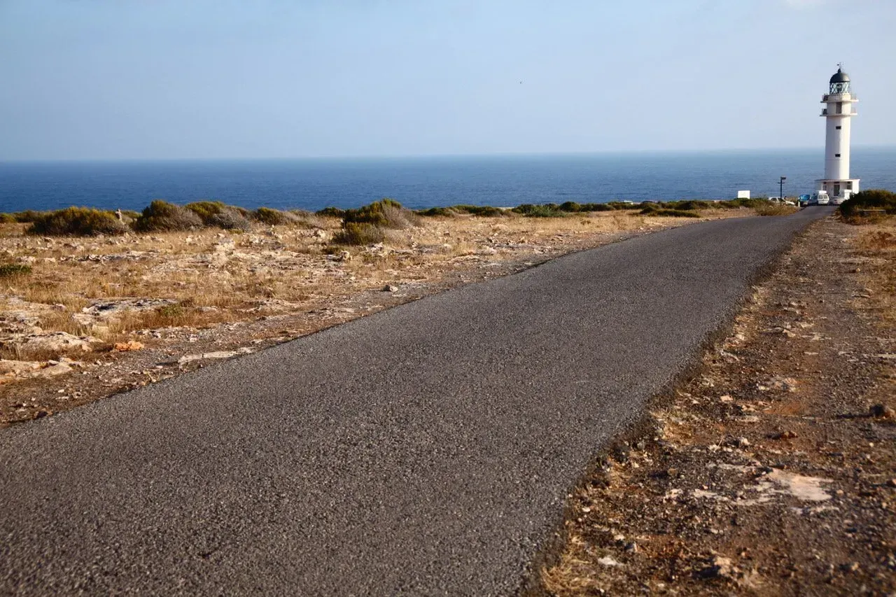 Uma estrada com um farol ao lado