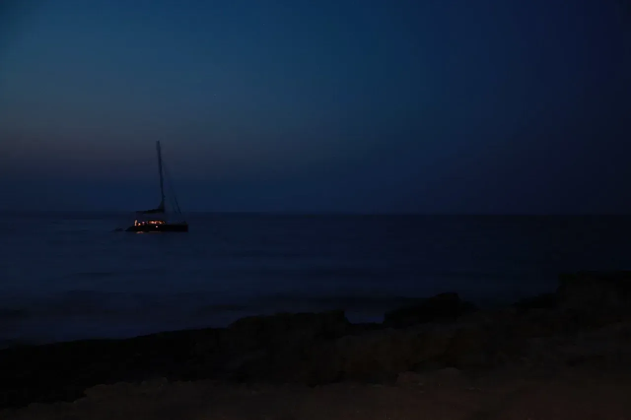 Um barco está flutuando sobre um corpo de água à noite.