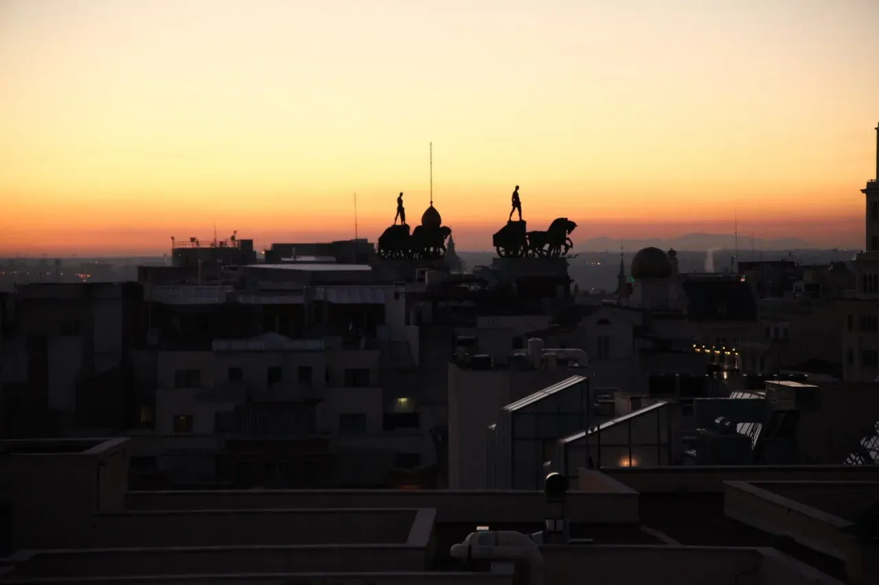 Um pôr do sol sobre uma cidade com uma estátua de um homem a cavalo