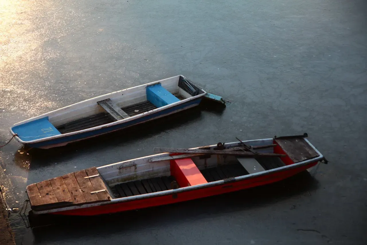 Dois barcos estão flutuando em cima de um corpo d'água