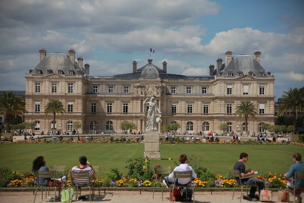 Um grupo de pessoas está sentado em cadeiras em frente a um grande edifício.