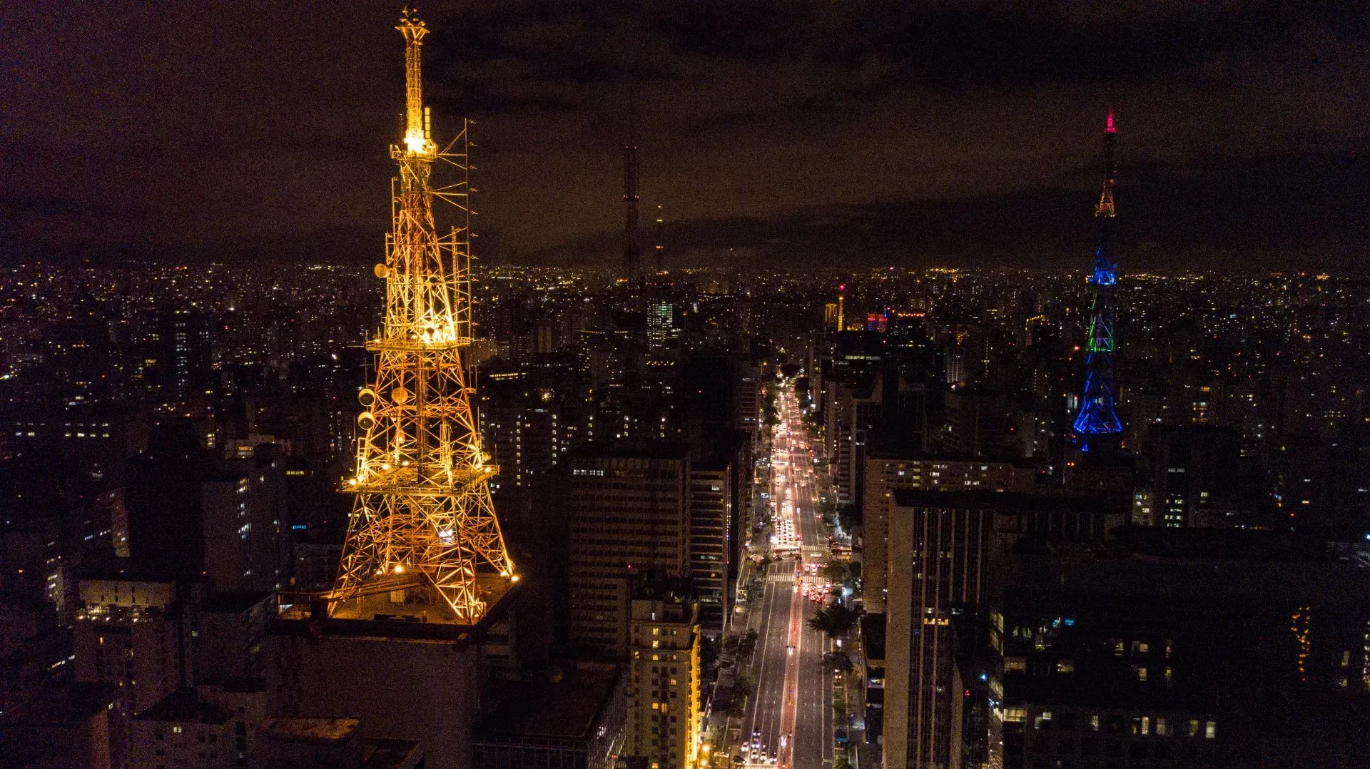 Uma vista aérea de uma cidade à noite com uma torre em primeiro plano
