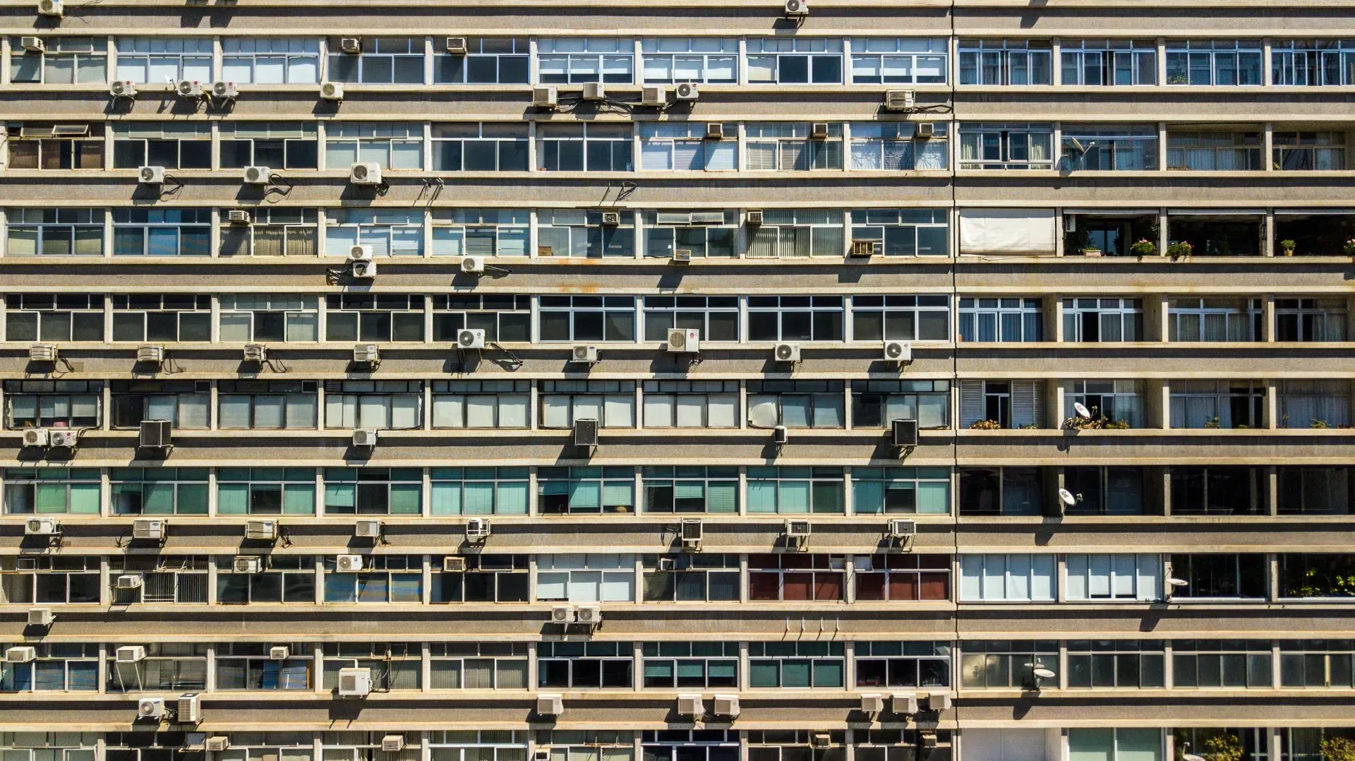 Um prédio grande com muitas janelas e aparelhos de ar condicionado nas laterais.