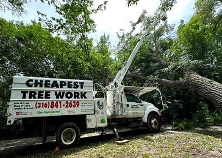 A white truck with a ladder on top of it is parked in a gravel lot.