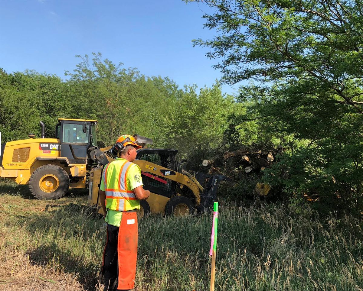 A man is standing in front of a bulldozer in a field.