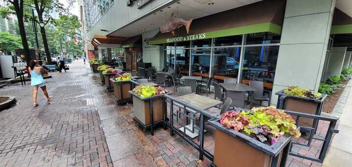 A woman is walking down a sidewalk in front of a restaurant.