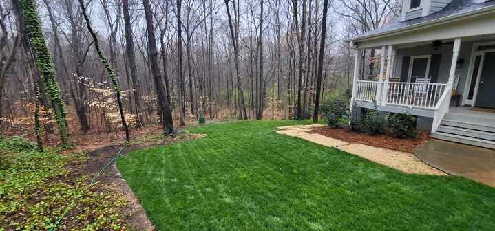 A house with a porch and a lush green lawn in front of it.