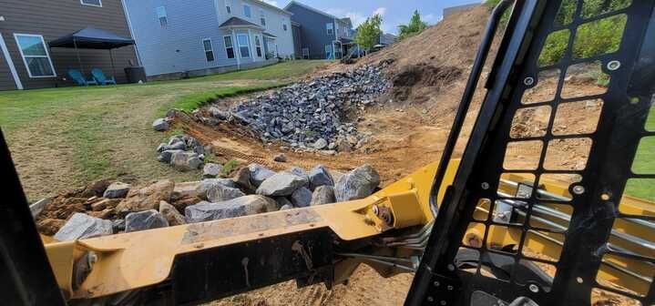 A bulldozer is moving dirt and rocks in a yard.