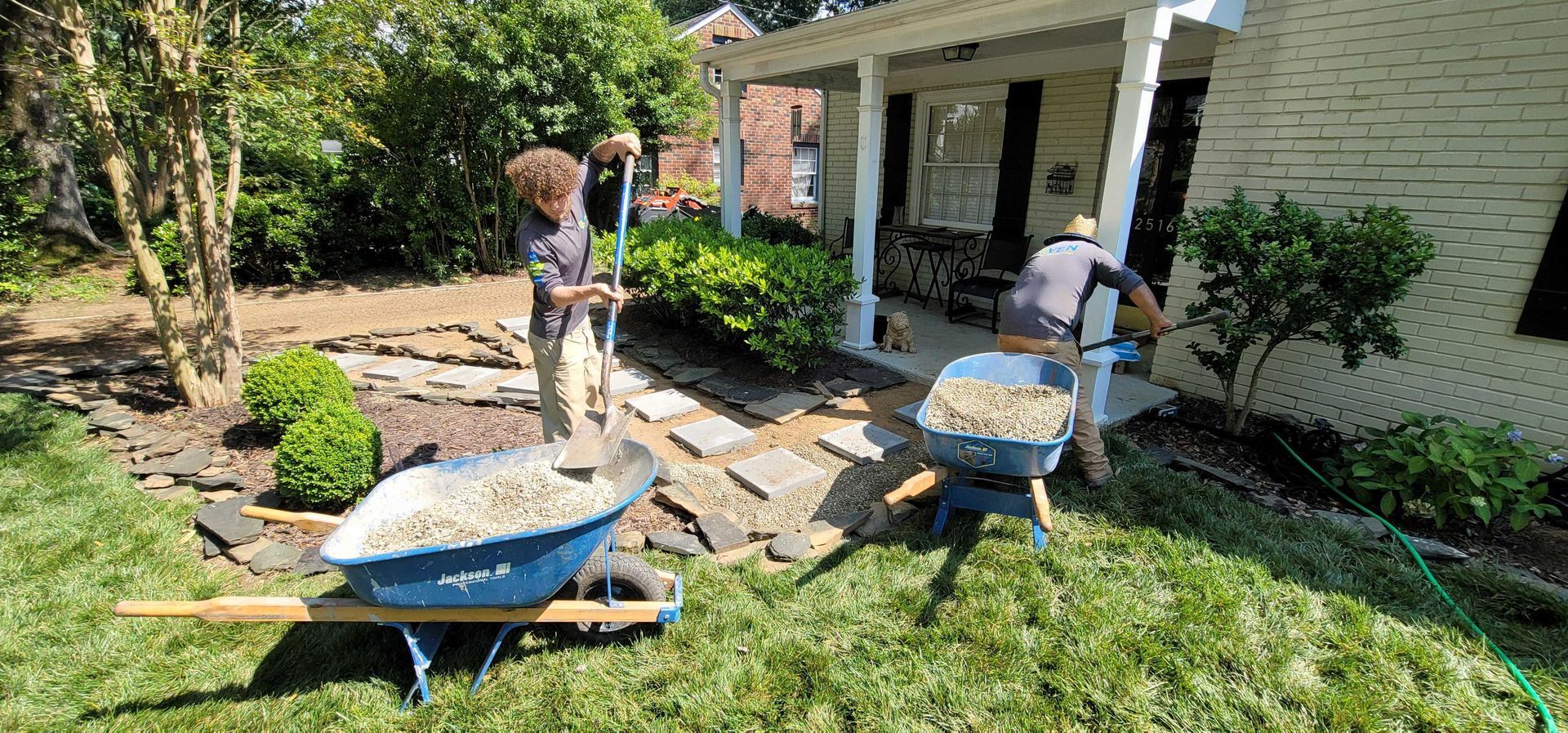 A man is pushing a wheelbarrow full of dirt in front of a house.