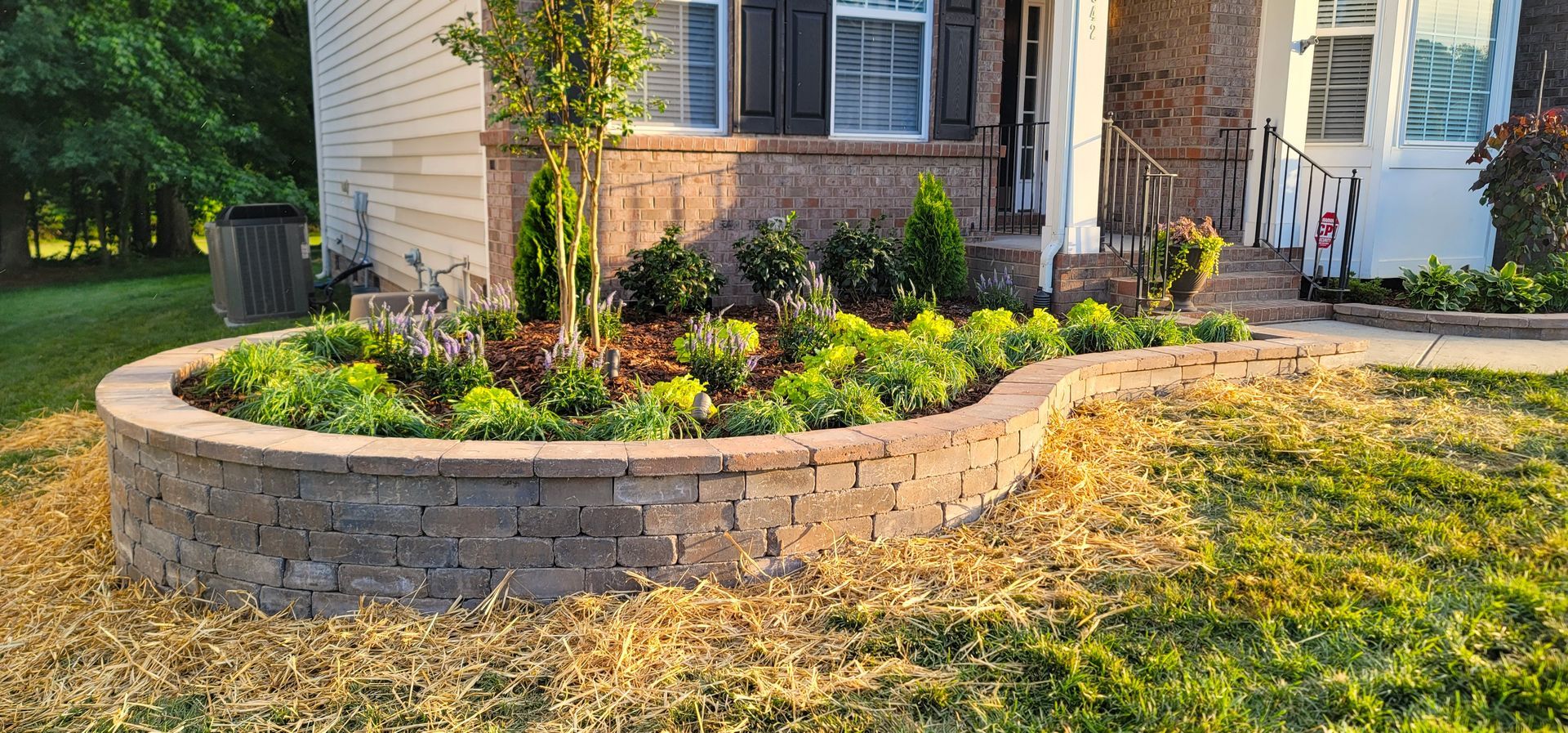 A house with a brick wall and a garden in front of it.